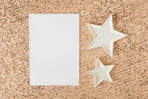 A blank paper on glittery sequins with decorative star shapes, ideal for festive designs.
